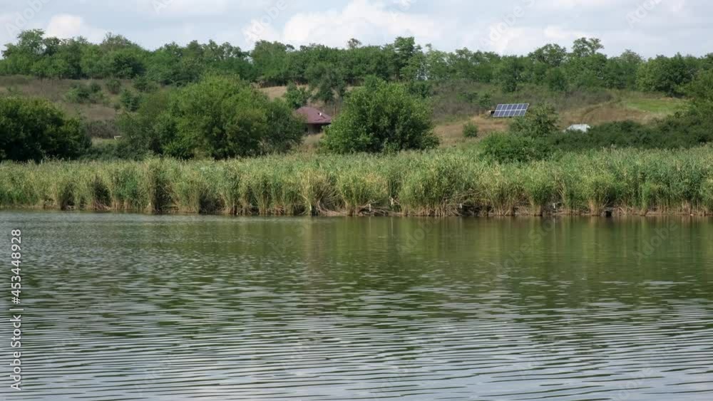 Lonely solar powered farm house on the river bank. Freestanding self-contained building using Solar Panels. Concept of eco-friendly construction, green energy, carbon footprint reduce Lonely solar powered farm house on the river bank. Freestanding self-contained building using Solar Panels. Concept of eco-friendly construction, green energy, carbon footprint reduce