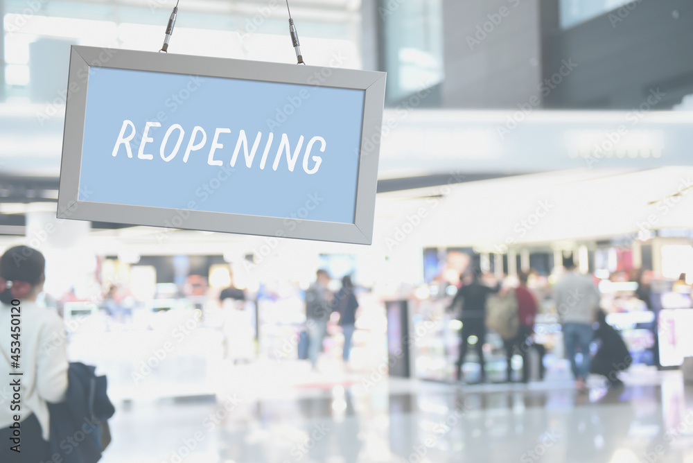 Reopening sign with  blurred crowd people walking in shopping department store as background
