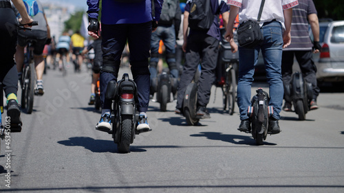 Man riding mono wheel, crowd of people riding bicycles in front of him. Partial view of contestants of street race. Concept of healthy lifestyle