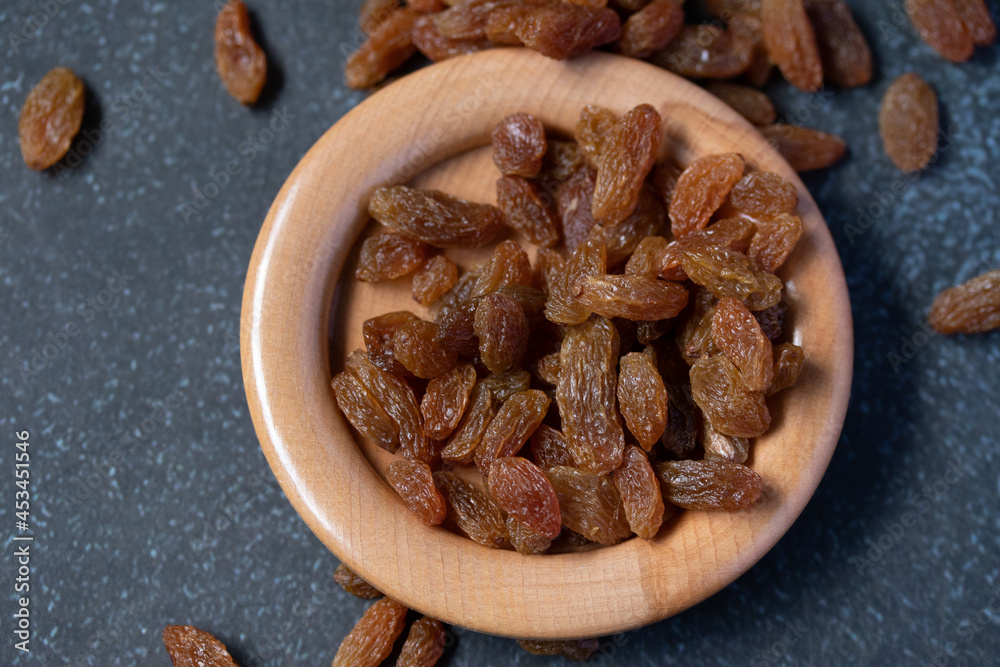 dried green raisins in wooden plate on black background dried green raisins in wooden plate on black background