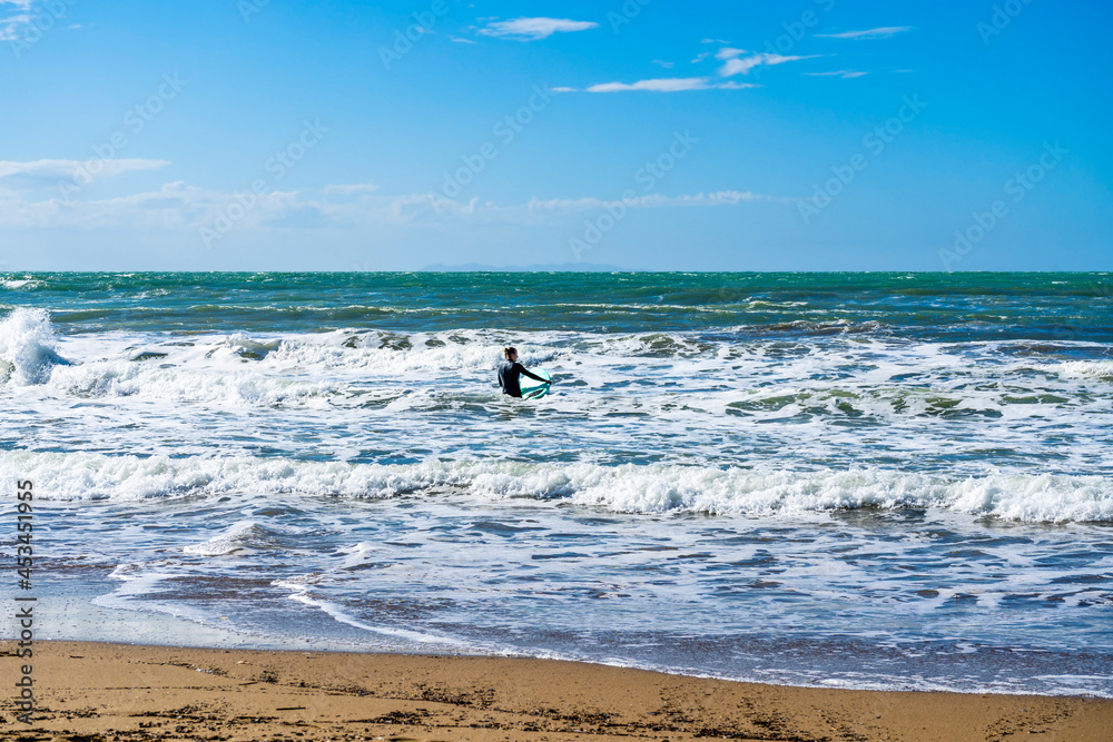 A surfer swimming in the waves with his surfboard, in the gulf of Baratti, Piombino, province of Livorno, Italy. A surfer swimming in the waves with his surfboard, in the gulf of Baratti, Piombino, province of Livorno, Italy.