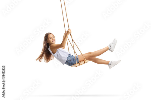 Beautiful girl with long hair swinging on a wooden swing photo