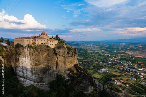 ギリシャ メテオラの断崖絶壁の岩山の上に建つ聖ステファノス修道院と奇岩群の隙間から覗くカランバカの街並み