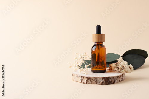 Cosmetic bottle with eucalyptus and wood on pastel beige background. Close up, copy space