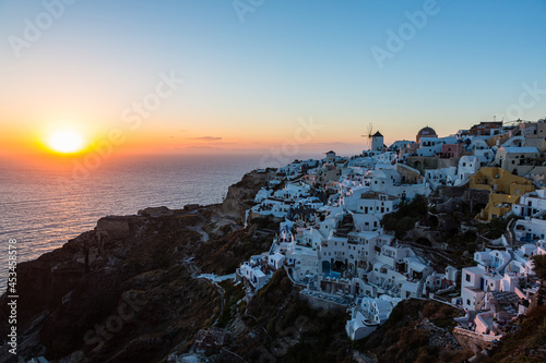 ギリシャ サントリーニ島のイアのイア・キャッスルから見えるマジックアワーの海に沈み行く夕日と白い街並みと風車