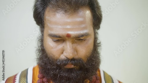 Close up shot of priest or hindu holy man applying vibhuti, bhasma or sacred ash to forehead before start of daily religious rituals. photo