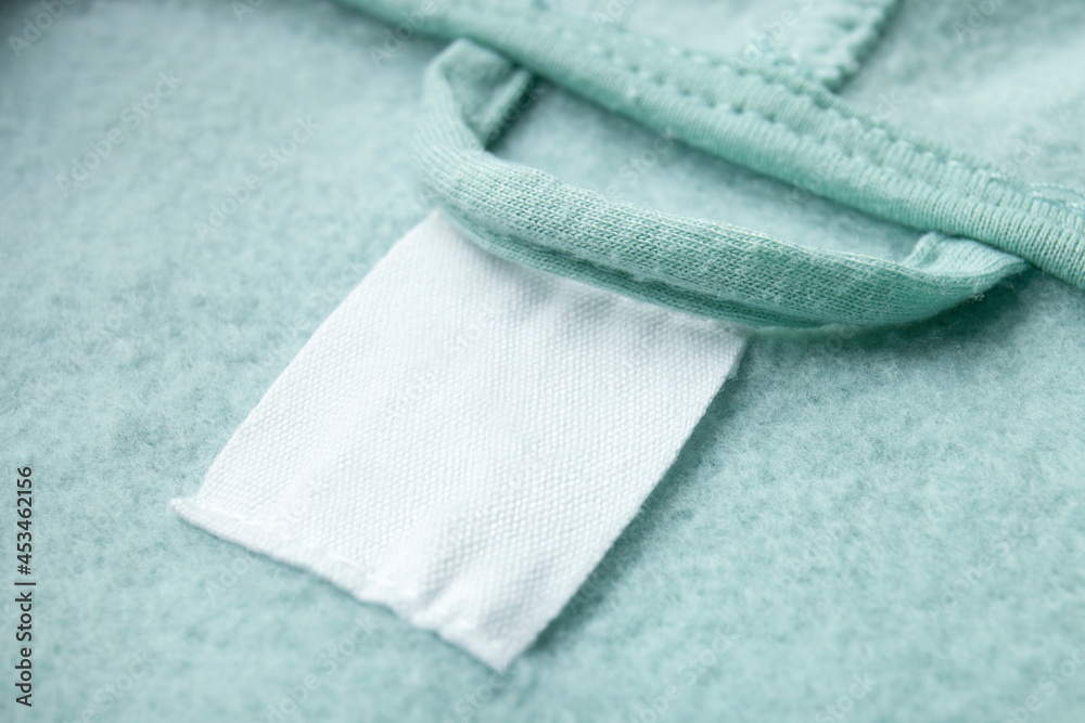 Cotton laundry care clothing label on fabric texture with place for text on fabric texture. Clothes with empty label or tag Cotton laundry care clothing label on fabric texture with place for text on fabric texture. Clothes with empty label or tag