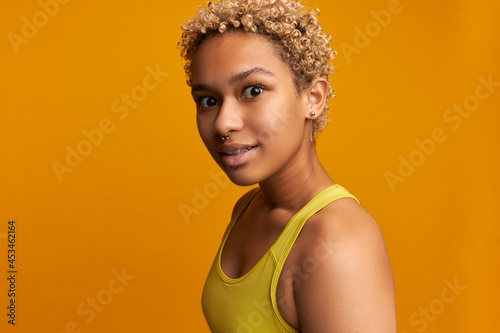 Close-up portrait of pretty dark-skinned woman of 20s making faces, fooling around on camera, isolated on orange background, with funny big eyes looking joyful and happy. People, emotions and feelings