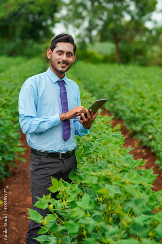Young indian agronomist or officer using tablet at agriculture field.