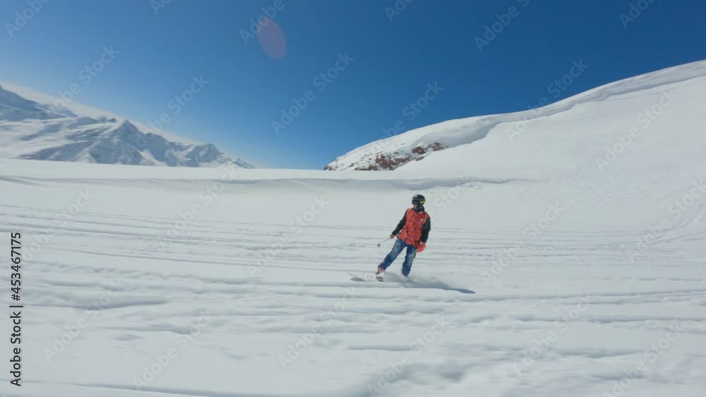 Aerial view fpv drone follow man enjoy freeride on snowboard extreme sport at clear snow field ski resort winter cinematic landscape. Active rider performing tricks on peak of mountain and sky Aerial view fpv drone follow man enjoy freeride on snowboard extreme sport at clear snow field ski resort winter cinematic landscape. Active rider performing tricks on peak of mountain and sky