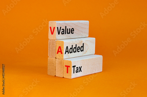 VAT, value added tax symbol. Wooden blocks with concept words 'VAT, value added tax'. Beautiful orange background, copy space. Business and VAT, value added tax concept.