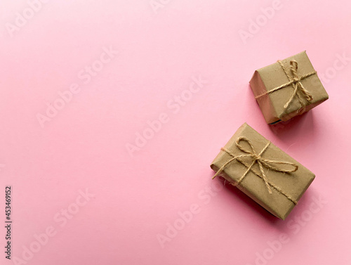A gift box wrapped in kraft paper on a pink background. View from above, flat lay, top view design. Minimalism. Concept sales, shopping, christmas holidays and birthday. © Ekaterina  Siubarova