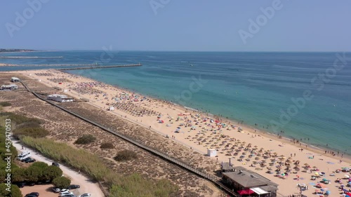 Aerial video, beautiful Portuguese beaches, near the tourist town, Vilamoura, Falesia, with a view of the dock. Tourists are sunbathing. photo