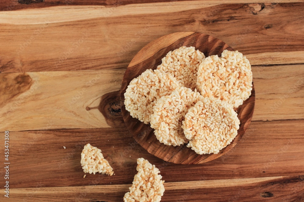 Ranginang, Rangginang, or Rengginang is One Indonesian Traditional Cracker Made from Rice (Glutinous Rice) and Frying. Served on Wooden Plate, Wooden Table Ranginang, Rangginang, or Rengginang is One Indonesian Traditional Cracker Made from Rice (Glutinous Rice) and Frying. Served on Wooden Plate, Wooden Table