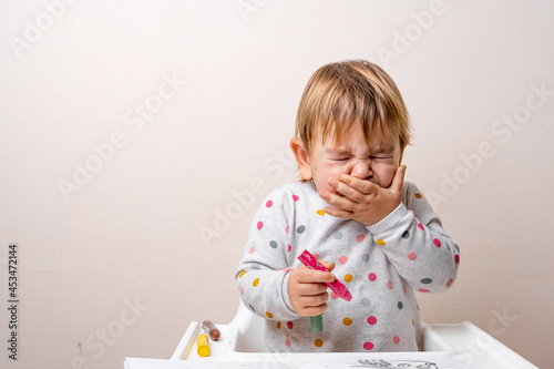 Toddler child sneezing while drying with crayons. Baby with allergy or cold from daycare or kindergarten. Germs paediatric medicine