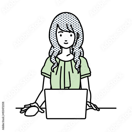 デスクで座ってPCを使っているオフィスカジュアルの女性