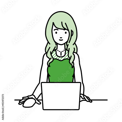 デスクで座ってPCを使っているドレスの女性