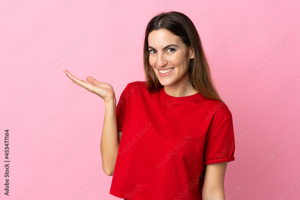 Young caucasian woman isolated on pink background holding copyspace imaginary on the palm to insert an ad Young caucasian woman isolated on pink background holding copyspace imaginary on the palm to insert an ad