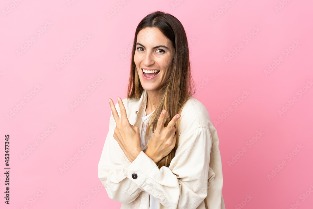 Young caucasian woman isolated on pink background smiling and showing victory sign Young caucasian woman isolated on pink background smiling and showing victory sign