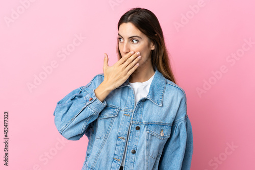 Young caucasian woman isolated on pink background doing surprise gesture while looking to the side