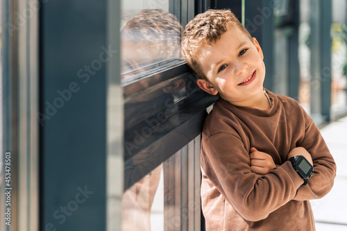 Cute modern boy leaning against the panoramic window at home