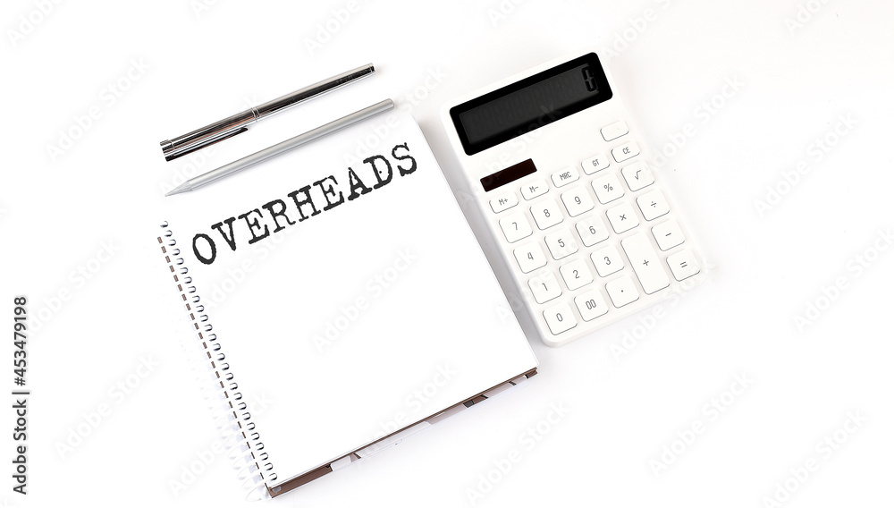 Notepad with text OVERHEADS with calculator and pen. White background. Business concept Notepad with text OVERHEADS with calculator and pen. White background. Business concept