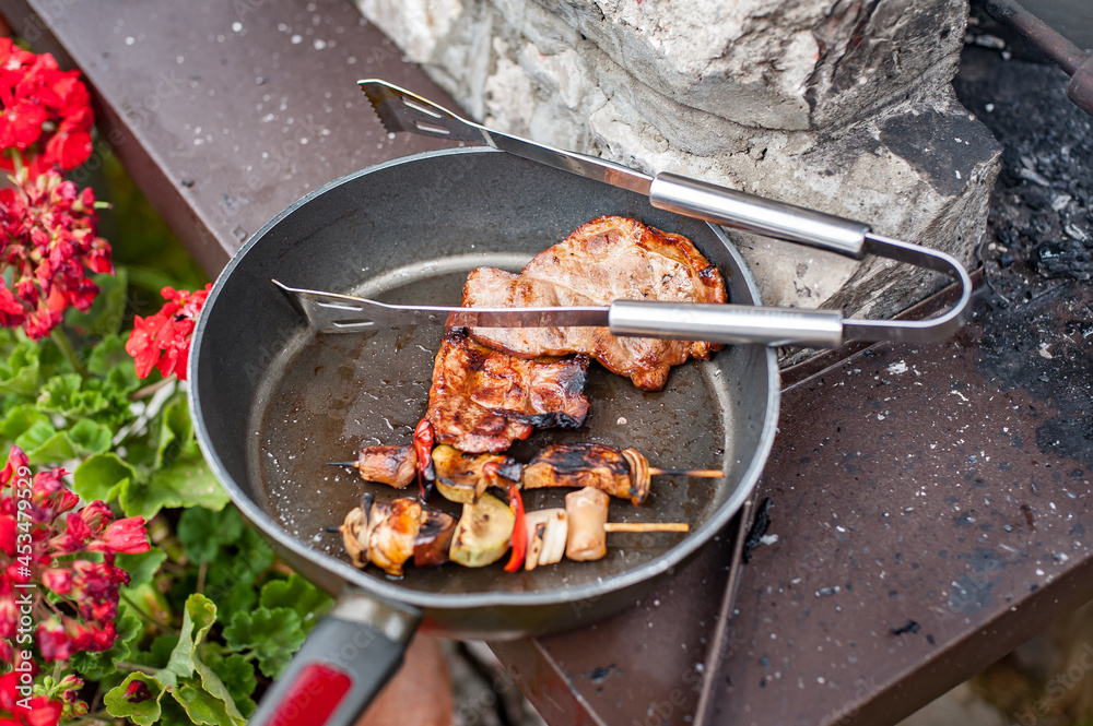 Delicious grilled meat in the cast iron grill pan with a variety of grilled vegetables skewers