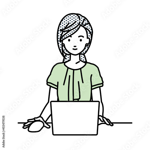 デスクで座ってPCを使っているオフィスカジュアルの女性