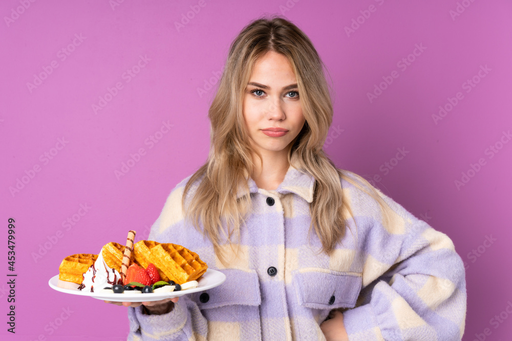 Teenager Russian girl holding waffles isolated on purple background angry Teenager Russian girl holding waffles isolated on purple background angry