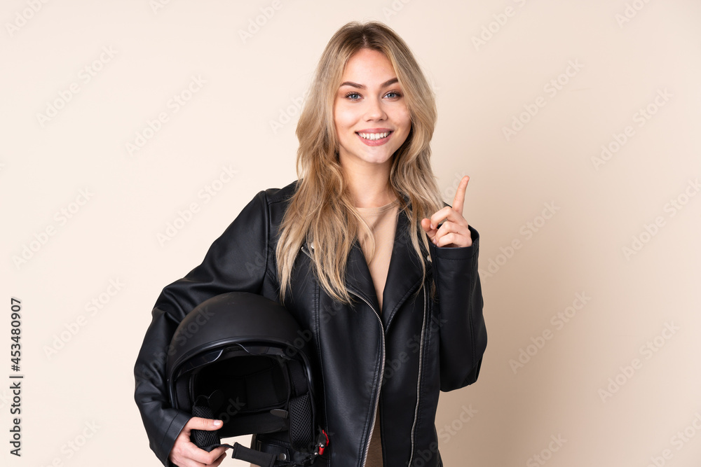 Russian girl with a motorcycle helmet isolated on beige background pointing up a great idea Russian girl with a motorcycle helmet isolated on beige background pointing up a great idea