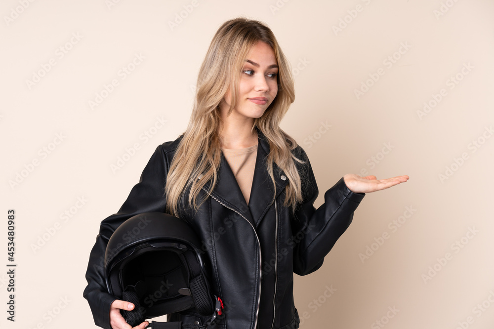 Russian girl with a motorcycle helmet isolated on beige background holding copyspace with doubts Russian girl with a motorcycle helmet isolated on beige background holding copyspace with doubts