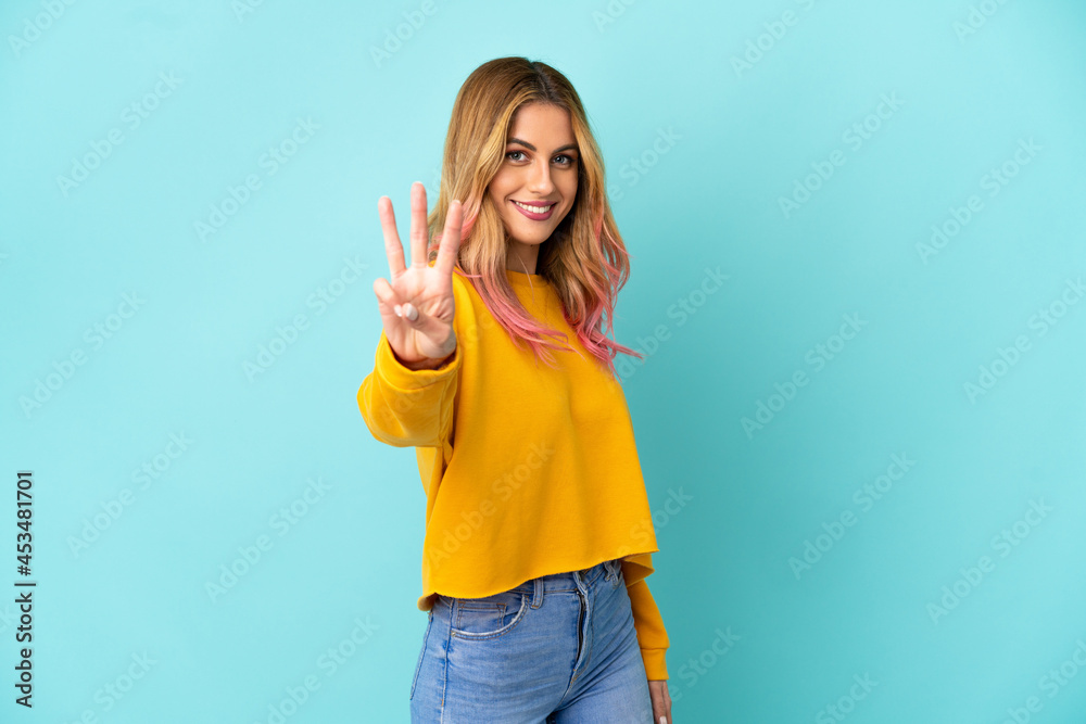 Young woman over isolated blue background happy and counting three with fingers Young woman over isolated blue background happy and counting three with fingers