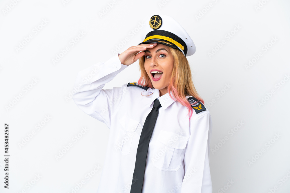 Airplane pilot over isolated white background doing surprise gesture while looking to the side Airplane pilot over isolated white background doing surprise gesture while looking to the side
