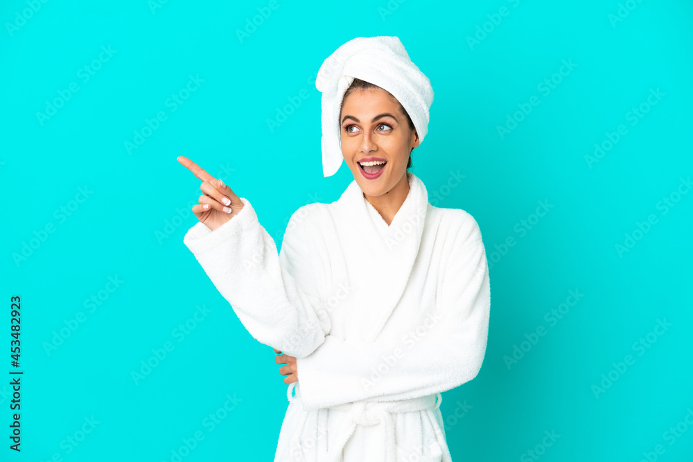 Young woman in a bathrobe over isolated blue background intending to realizes the solution while lifting a finger up Young woman in a bathrobe over isolated blue background intending to realizes the solution while lifting a finger up
