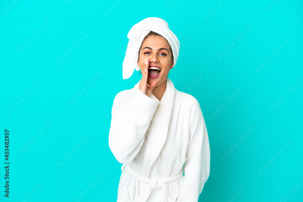 Young woman in a bathrobe over isolated blue background shouting with mouth wide open Young woman in a bathrobe over isolated blue background shouting with mouth wide open