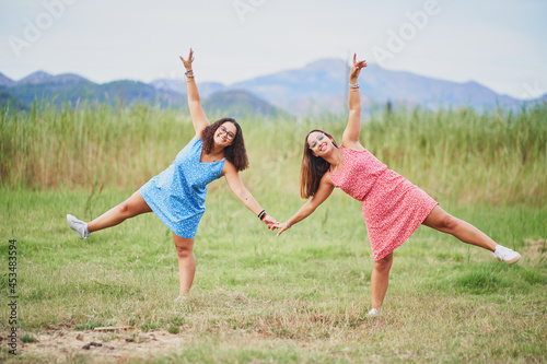 Couple of women on red and blue dress posing and having fun on green land