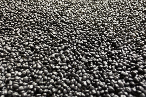 Polypropylene granule close-up. Plastic black granulated crumb. Background abstract texture. Black chemical granules for industrial plastic production. Polymer plastic. Compound polymer. Macro
