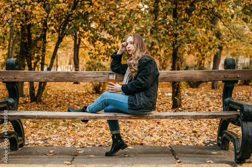 Zero Waste Fall Activities, Things to Do for Fall Season, Environmental friendly, eco living. Enjoying wonderful autumn season. Young beautiful woman with reusable coffee cup walk in fall autumn park.