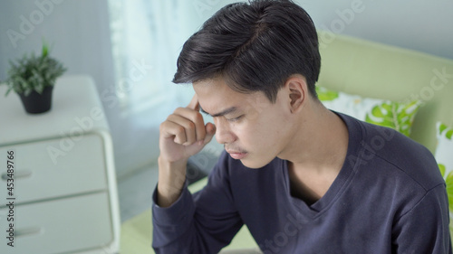 young asian man thinking about something at home