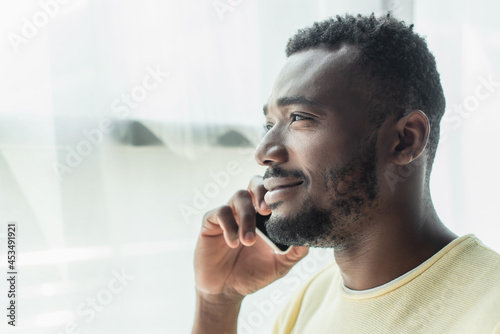 cheerful african american man talking on cellphone at home
