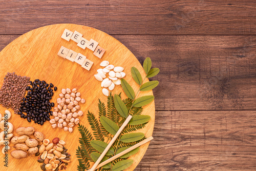 Round table with legumes and seeds with greens for vegans and vegetarians on rustic and natural wooden table.