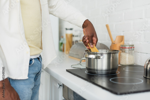 Fototapeta Naklejka Na Ścianę i Meble -  cropped view of young african american man cooking spaghetti in kitchen