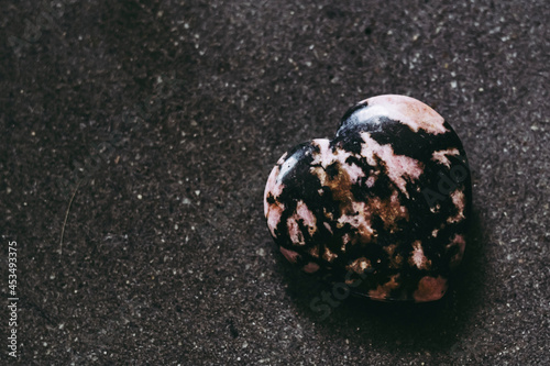 Coeur en pierre de rhodonite sur un fond noir - Minéral naturel photo