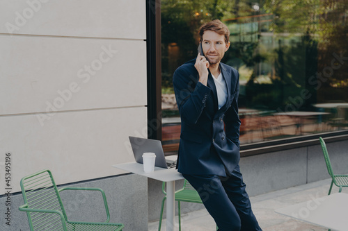 Outdoor shot of busy man entrepreneur solves probems distantly has telephone conversation