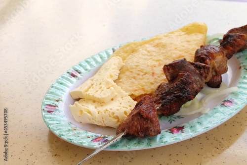 Lamb meat on the grill. Served with goat cheese and tortilla on a platter. photo