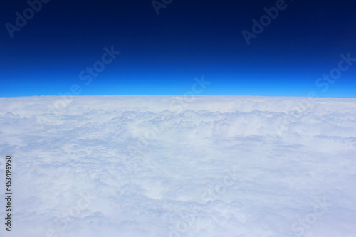 Cloud and sky pastel colors abstract nature background. airplane and green landscape, river, mountain, clouds background. View from the airplane window. Airplane wing flying above the clouds. Top view © Natalia Bo