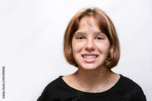 Portrait of the young girl of 12-13 years who sincerely smiles on a light background, shows the healthy white teeth, the girl is glad that treated all teeth. Dental concept