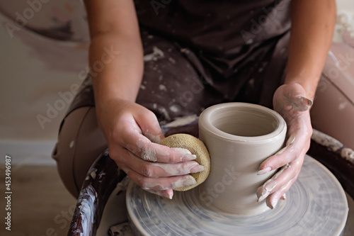 Woman hands working on pottery wheel and making a pot. Young woman making pottery on the wheel. sculpts pot from clay.