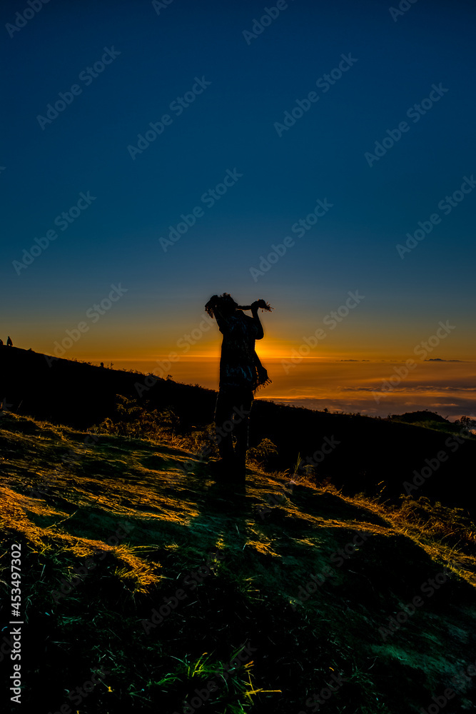 silhouette of a person standing on the top of the mountain