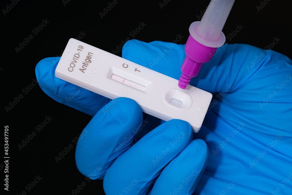 Surgical gloves, placing the sample into the covid-19 antigen diagnostic test device, Physician who owns a COVID-19 antigen test kit with a COVID-19 2019-nCoV viral disease test kit, Rapid COVID-19.